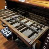 E tra contenitori d�inchiostro, tagliacarte in argento, allungamatite in legno e cassettiere con caratteri mobili per la stampa...